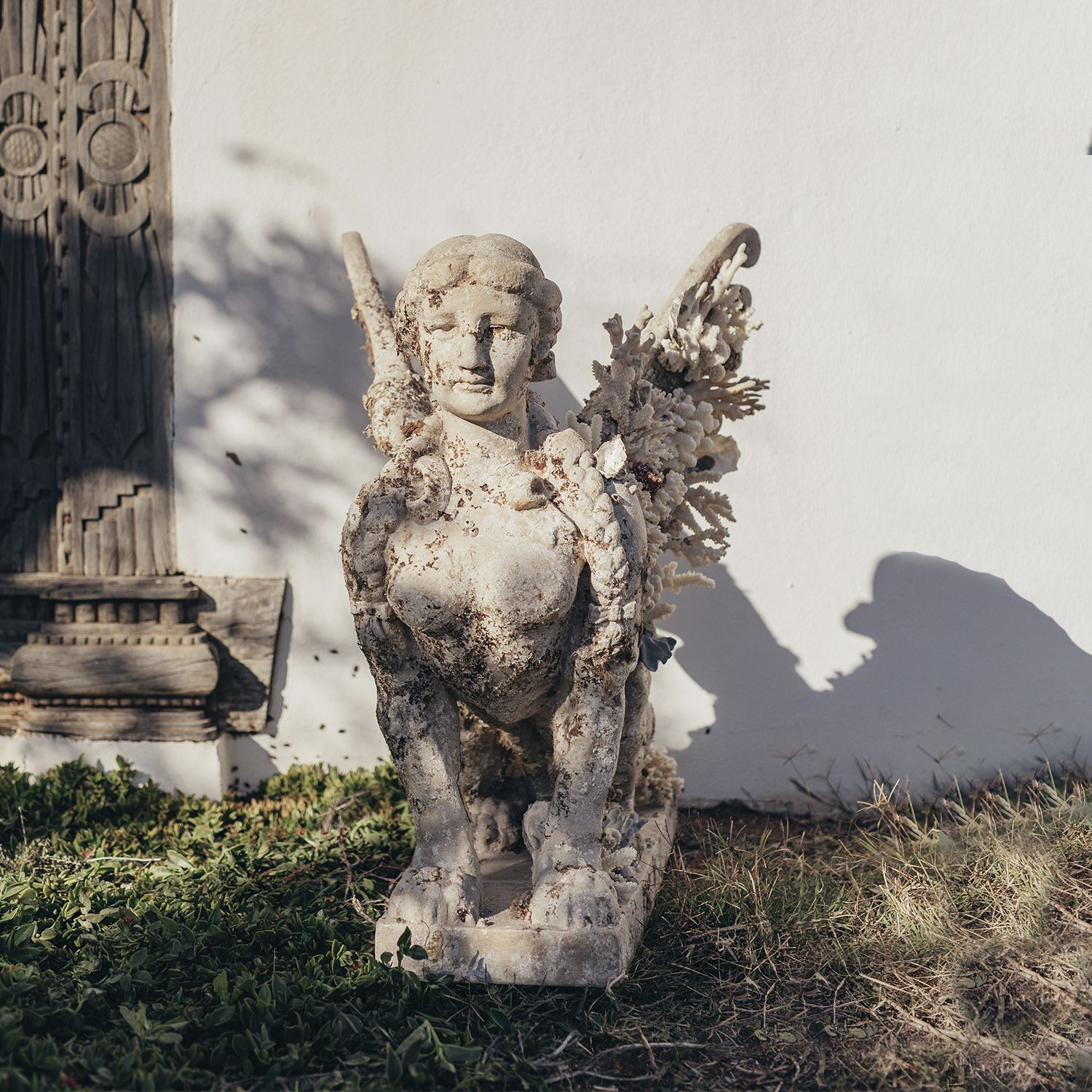 Escultura Esfinge, en mármol reconstituido, de 83 cm de alto, cultivada bajo el mar y con coral. Elemento decorativo en patio exterior.